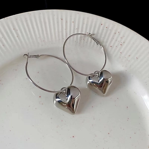 Detailed view of silver butterfly heart hoop earrings resting on a white ceramic plate