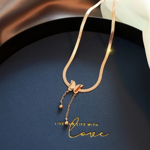Detail of rose gold butterfly pendant with matte texture and elegant tassel chains on snake chain