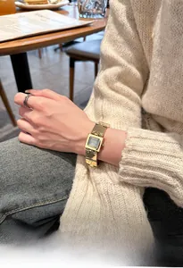 Détail d'une montre carrée dorée de luxe avec bracelet en acier inoxydable