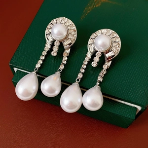 Macro detail of silver vintage earrings with rhinestones and white teardrop pearls