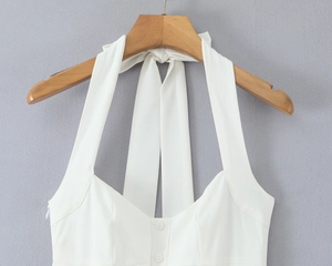 Detail of white halter neck top with vertical button closure and V-neckline on wooden hanger