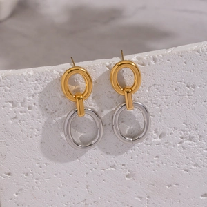 Vue macro de boucles d'oreilles ovales bicolores or et argent sur pierre