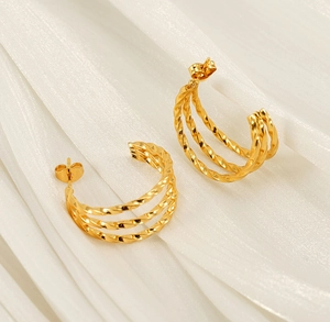 Close-up of golden multi-layer twisted rope hoop earrings with textured finish