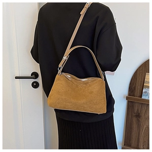 Detailed texture of brown suede shoulder bag with adjustable strap and silver buckle