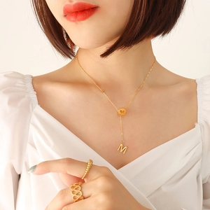 Golden Y-shaped tassel necklace with letter M pendant and matching hollow ring on model