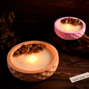 Pink and orange geometric diamond pattern candle bowls with dried rose buds on wood
