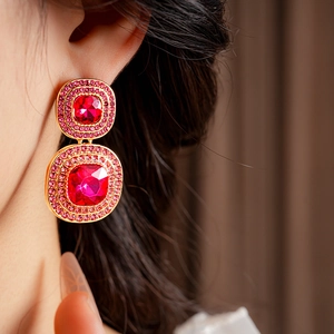 Close-up of vintage gold double-layer oval earrings with pink gems worn by a model