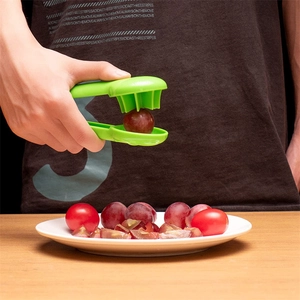 Macro shot of a green plastic grape slicer cutting small fruits into even pieces