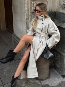 Detail of a chic long cream trench coat in faux leather finish with stylish double buttons