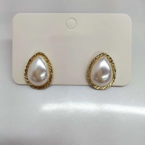 Detail of teardrop pearl earrings with gold metal edges on a display card