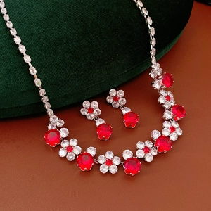 Detail of red zircon flower necklace and earrings set on green velvet luxury display