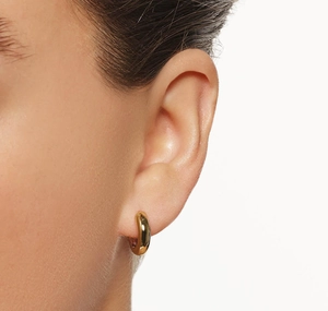 Close-up of chunky gold S925 sterling silver hoop earrings worn on a model's ear