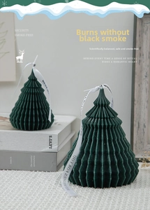 Detail of green origami Christmas tree candle with Best Wishes ribbon on cozy blanket