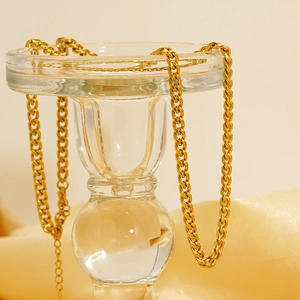 Polished 18K gold-plated stainless steel Cuban link necklace on elegant glass stand