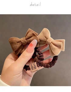 Detail of plush bow hair ties in brown and khaki with decorative Hand Made labels