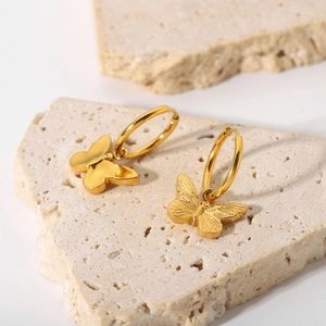 Vintage golden butterfly pendant earrings in stainless steel on natural stone background