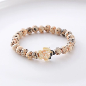 Detailed close-up of dalmatian jasper stone beads with a cute sea turtle pendant charm