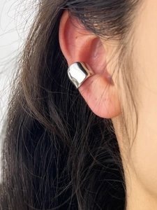 Detailed view of polished silver horseshoe-shaped ear cuff worn on the upper ear cartilage