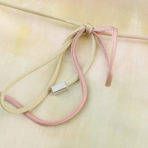 Détail macro des lanières en satin pastel avec une boucle en métal argenté poli élégante