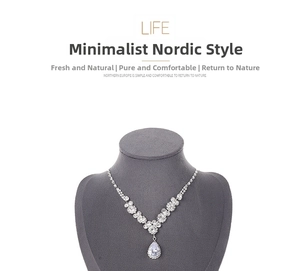 Macro detail of a silver-toned necklace with pear-cut cubic zirconia on a gray velvet stand