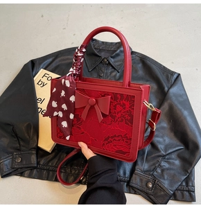 Close-up of red wedding handbag featuring lace jacquard texture and decorative silk scarf