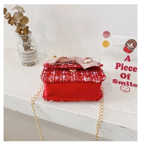 Detailed shot of red tweed girls crossbody bag with pearl bow and golden chain