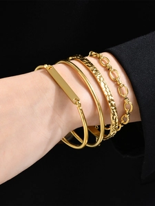 Detail of four-piece gold bracelet set including hammered and Cuban chain designs