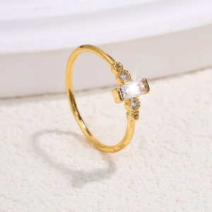 Macro shot of gold-plated ring with rectangular clear gemstone and round side stones