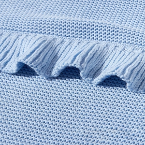 Macro view of light blue cotton knit baby blanket featuring soft ruffle edge details