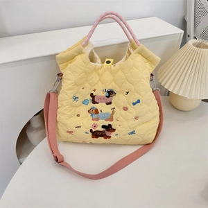 Close-up of cute cartoon dog embroidery and quilted fabric texture on yellow crossbody bag