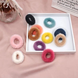 Detailed view of colorful plush scrunchies in various candy colors on a soft pink background