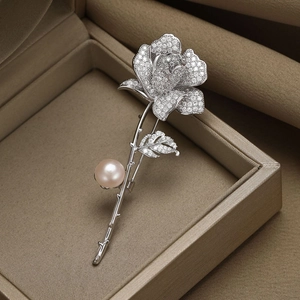 Détail macro d'une broche rose argentée avec pétales en zircon et perle rose élégante