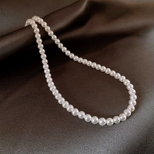 Classic single-strand white pearl necklace featuring round glossy beads on silk background