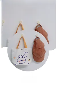 Detail of white canvas tote bag with rabbit print and yellow handle on a wall hook