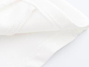 Close-up of high-quality sewing and fabric texture on white sleeveless vest and trousers