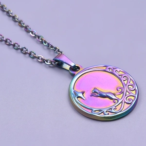 Detailed close-up of rainbow heart pendant with moon and cat motif on purple surface