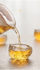 Close-up of frosted hammered glass tea cup with clear tea pouring through transparency