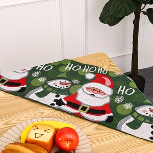 Close-up of green woven Christmas table runner with Santa and snowman embroidery
