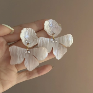 Close-up of elegant double-layered resin flower earrings with small inlaid crystals