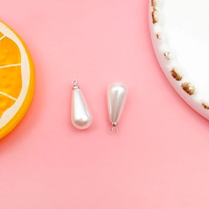 Macro detail of white teardrop pearl pendants with silver caps for DIY jewelry making