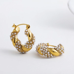 Macro shot of gold-plated twisted hoop earrings with micro pearls and diamond cluster detail