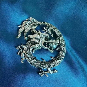 Detailansicht einer Vintage-Drachenbrosche mit Kristallen und weißer Perle auf Seide