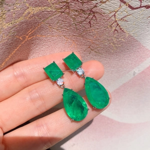 Detail of pear-shaped emerald green earrings with large water drop gemstones