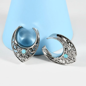 Hollow stainless steel ear gauges with blue opal stone inlay on a professional studio setup