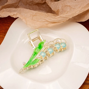 Detail of lily of the valley hair claw clip with golden finish and blue floral beads