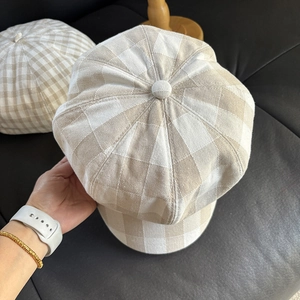 Detail of light beige plaid newsboy caps with textured linen fabric and top button