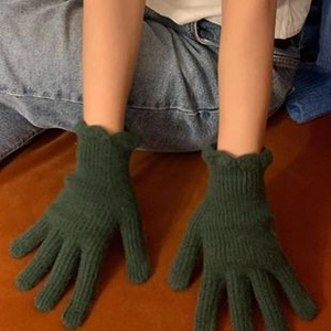 Detalle de guantes de punto de lana verde oscuro con puños festoneados y textura suave