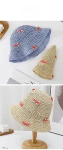 Détail de chapeaux de paille avec nœuds roses sur supports en bois pour look de plage