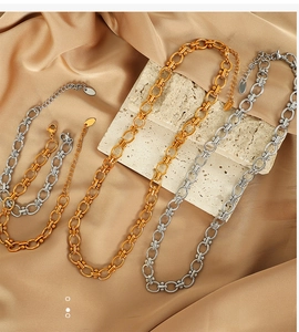 Detail of gold and silver titanium steel necklaces on silk fabric with stone props