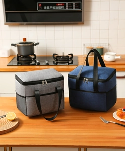 Close-up of waterproof cationic insulated lunch bags in gray and navy blue on wood table